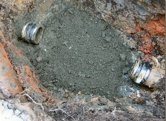 Процесс укладки бетона в небольшую яму с проходящими трубами